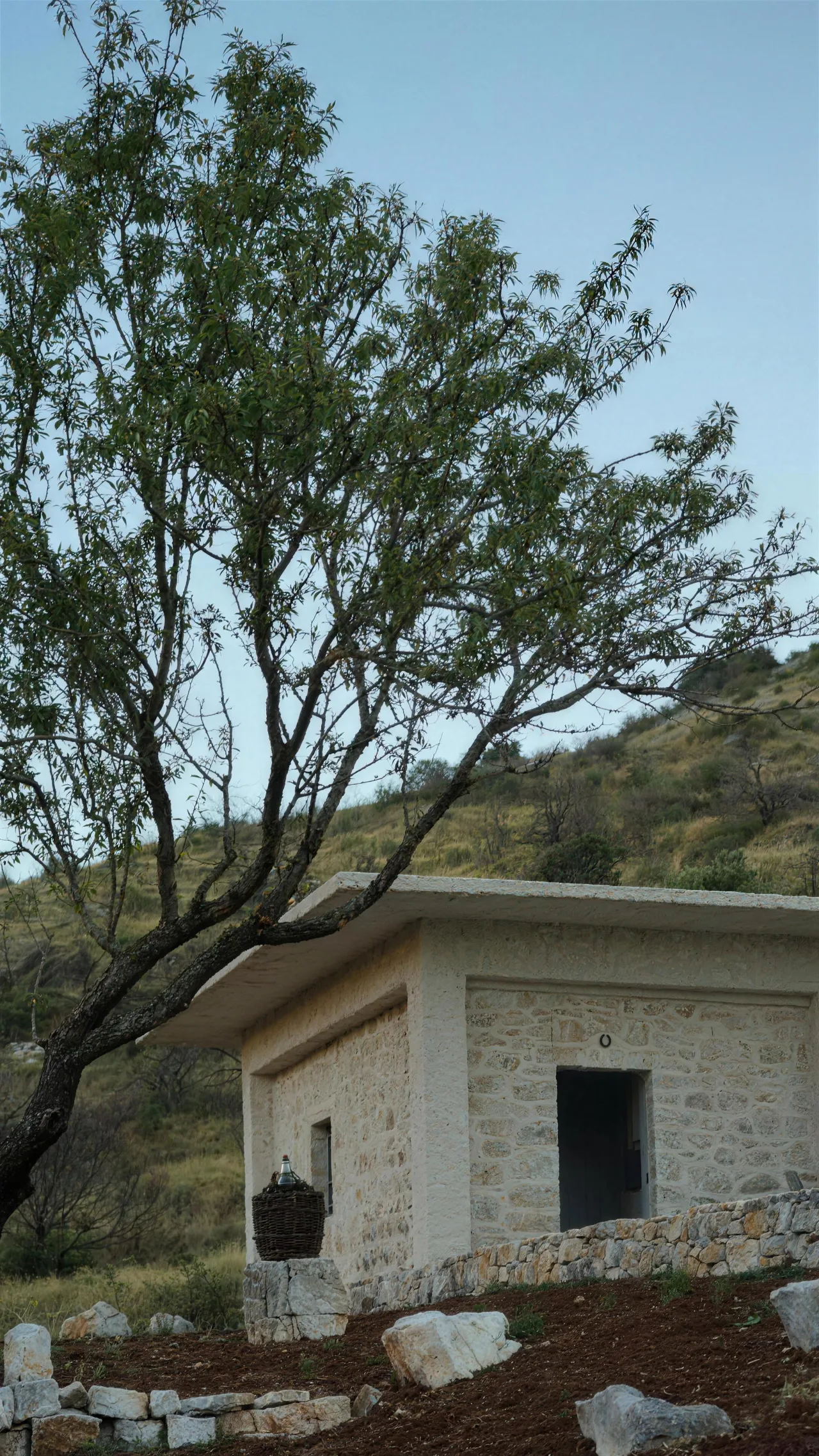 The whitewashed estate building behind the dry-stone wall at dusk