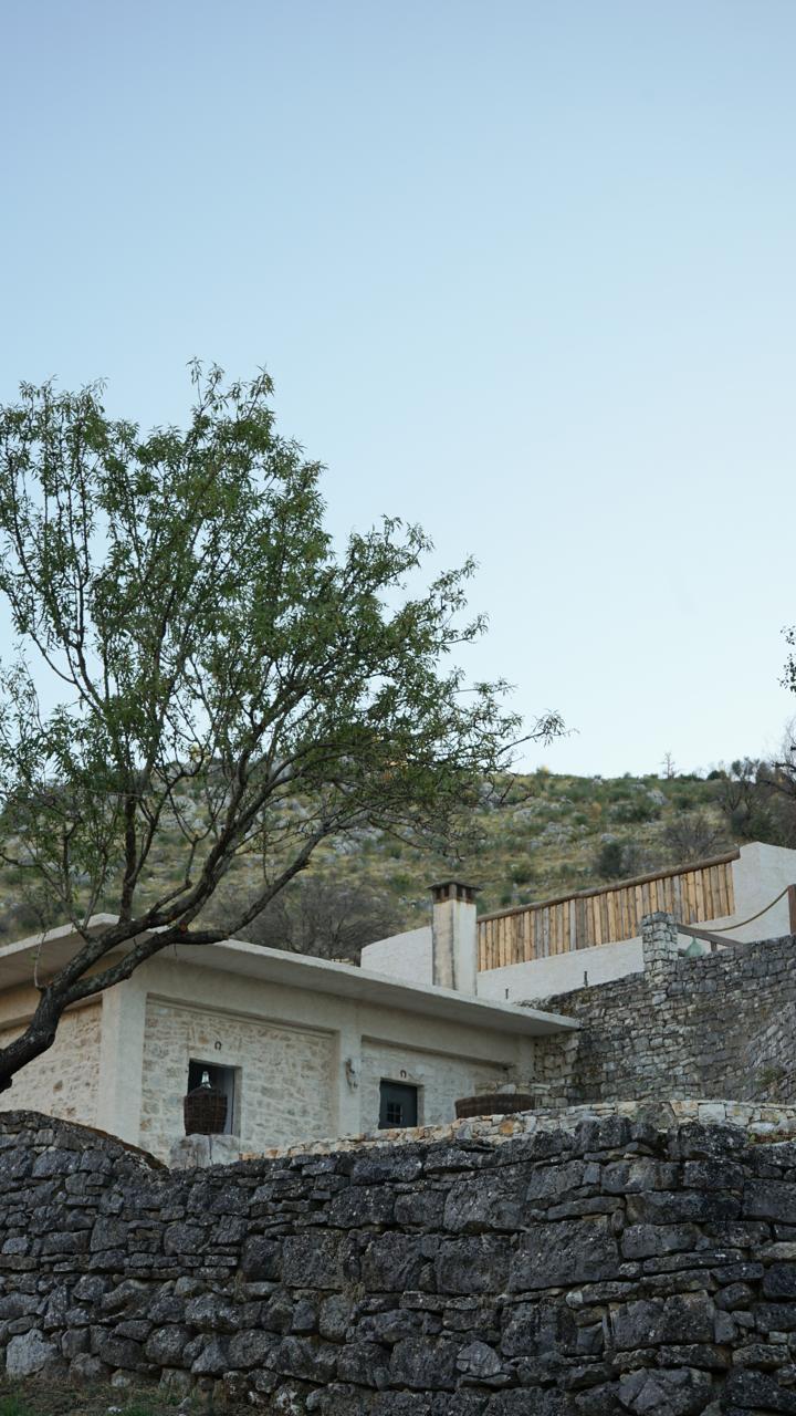 The estate building behind the dry-stone wall, the timber terrace railing above it on the hillside